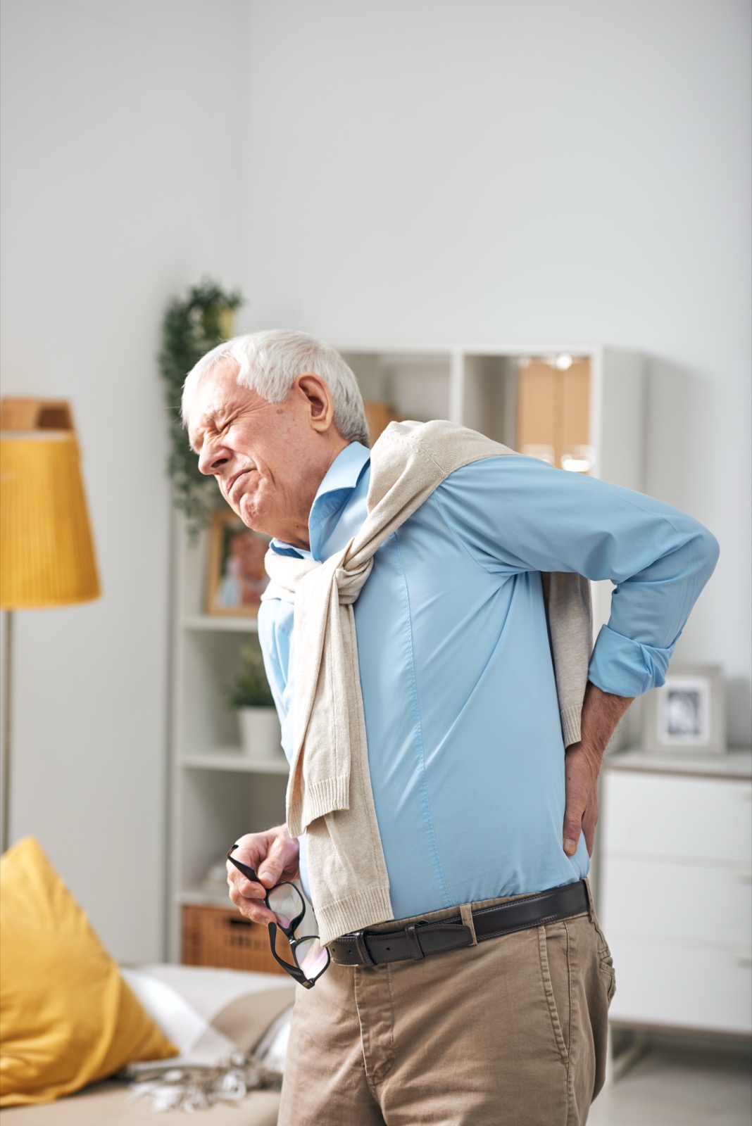 Older man holding his lower back in pain at home — acupuncture for back pain in Boca Raton