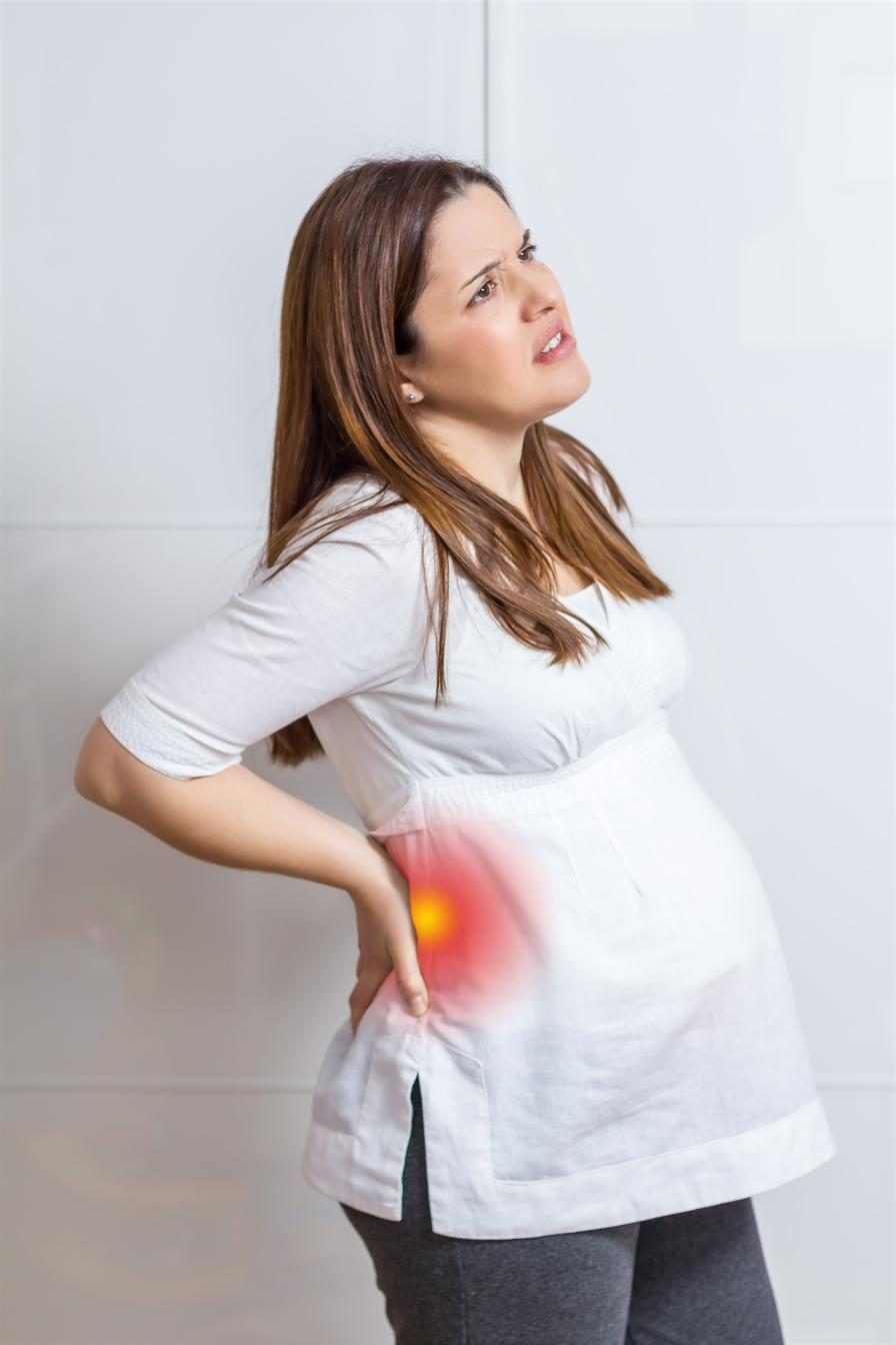 Pregnant woman holding her lower back in discomfort — acupuncture for pregnancy back and pelvic pain in Boca Raton by Ronen Rosenblatt Nir